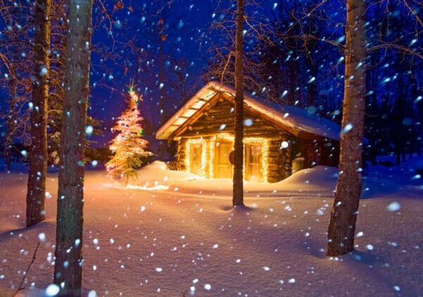 Winter scene of heavy falling snow and a historic log cabin with christmas lights in Wiseman, Alaska